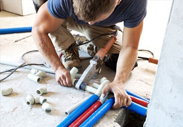 Professional plumber joining pipes on the groundProfessional plumber joining pipes on the ground