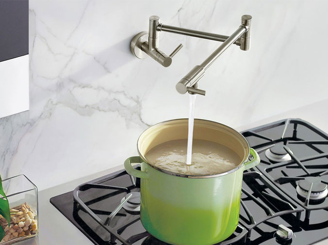 Stailess wall faucet filling a green cooking pot - Weinstein Kitchen & Bathroom Showroom West Chester